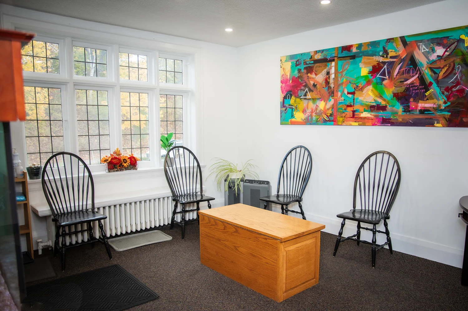 The bright waiting room at High Park Smile Studio, with chairs, a wooden coffee table, and colourful wall art